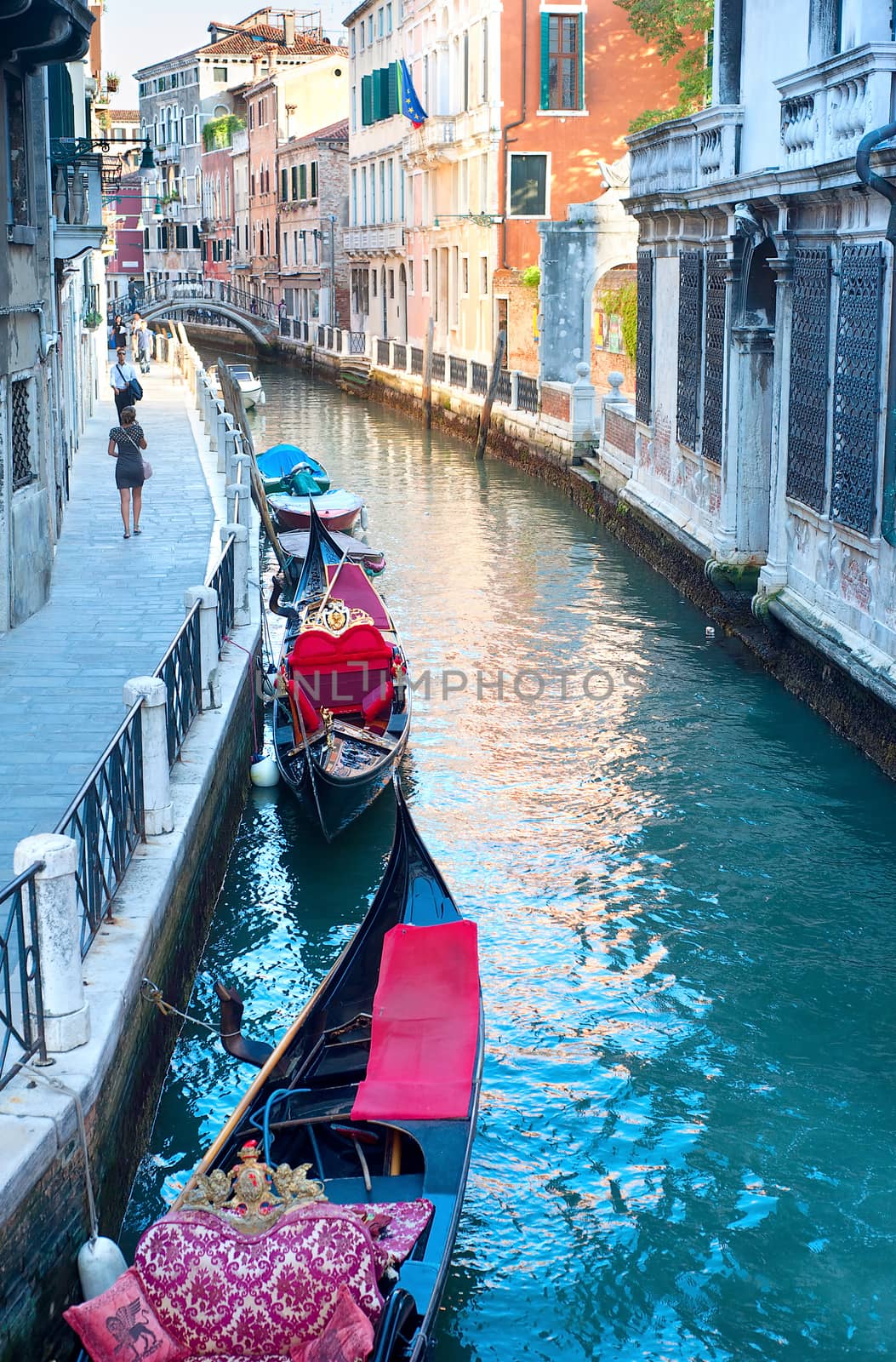 VENICE - SEPTEMBER 6, 2013: Gondolas waiting for tourists on a small Venetian canal  in Venice. More than 20 million tourists come to Venice annually.
