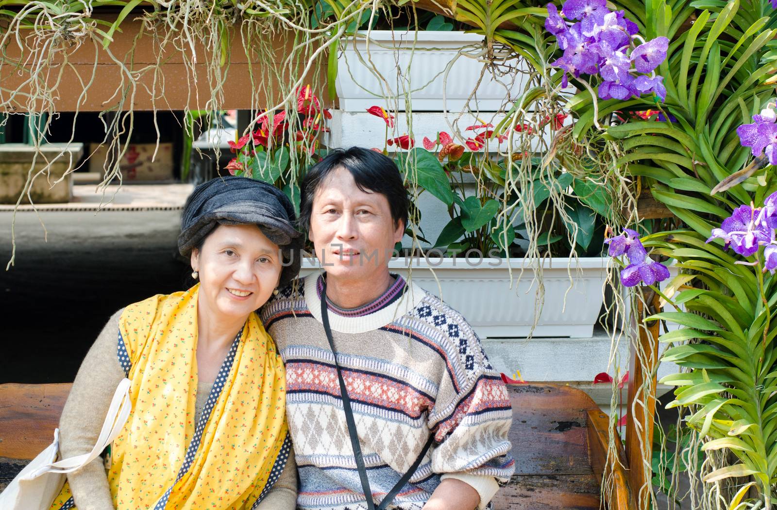 Smiling happy seniors couple in garden by siraanamwong