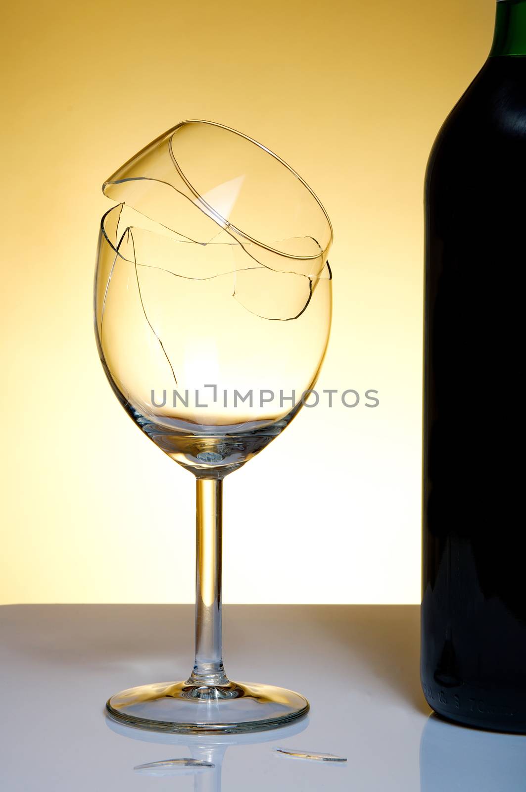 Vine bottle and broken glass on orange background