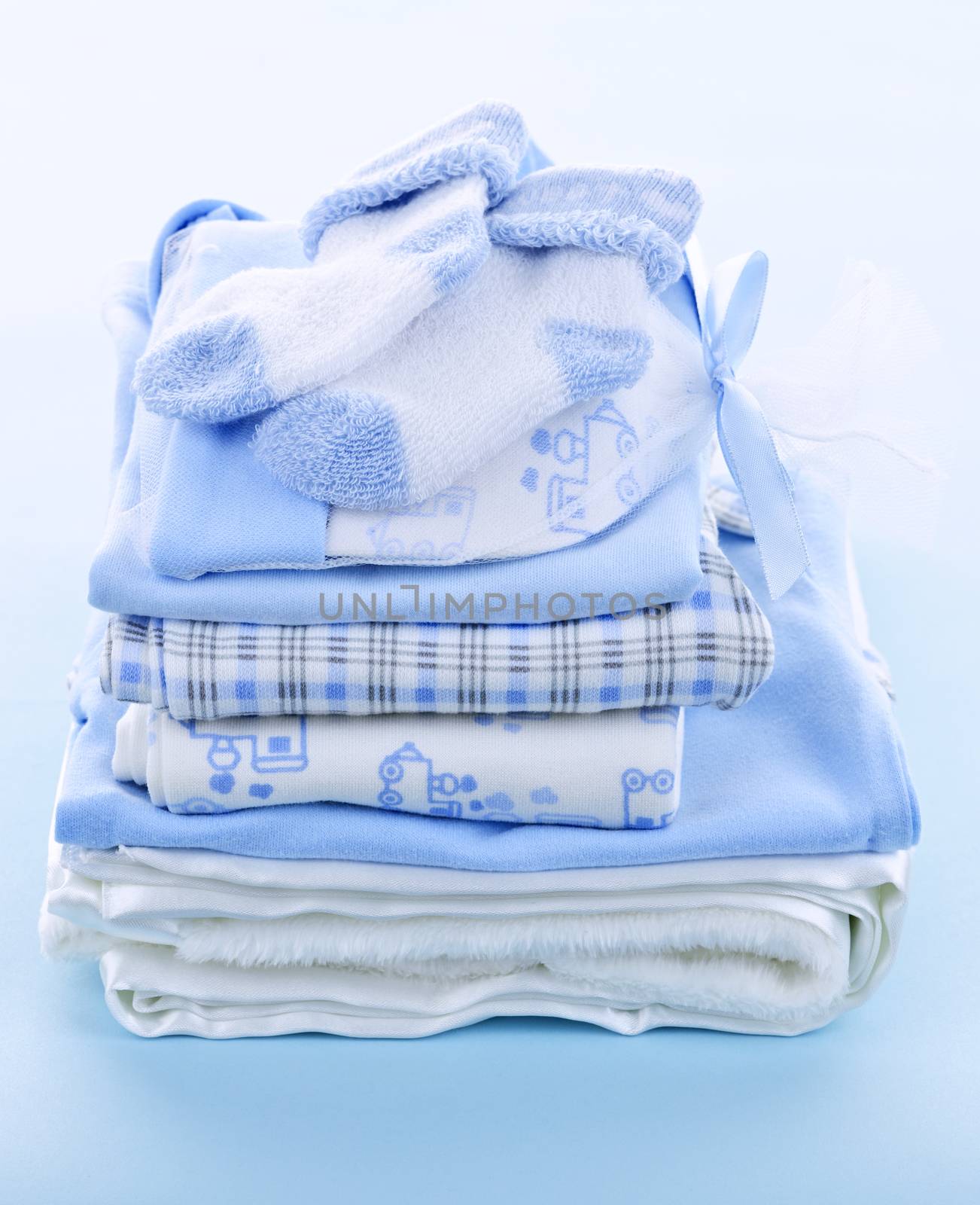 Stack of boy infant clothing for baby shower on blue background