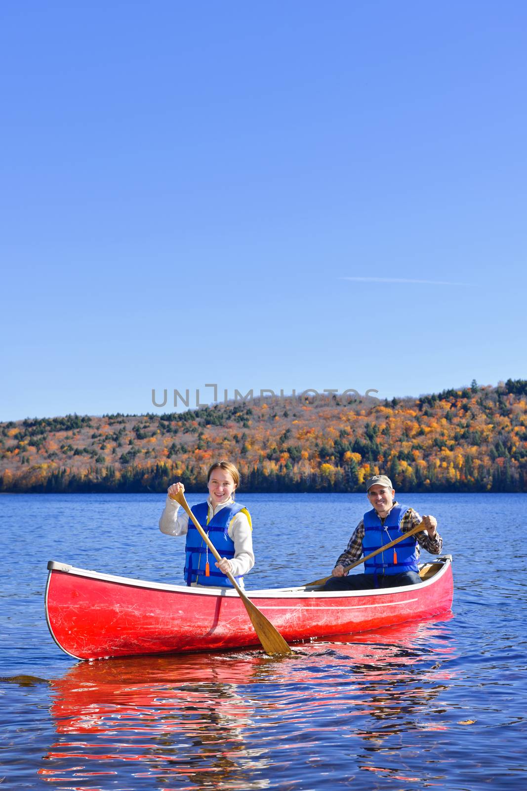 Canoe trip on scenic lake in fall by elenathewise