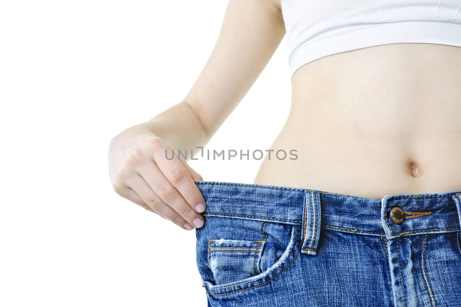 Fit young woman in loose jeans after losing weight isolated on white