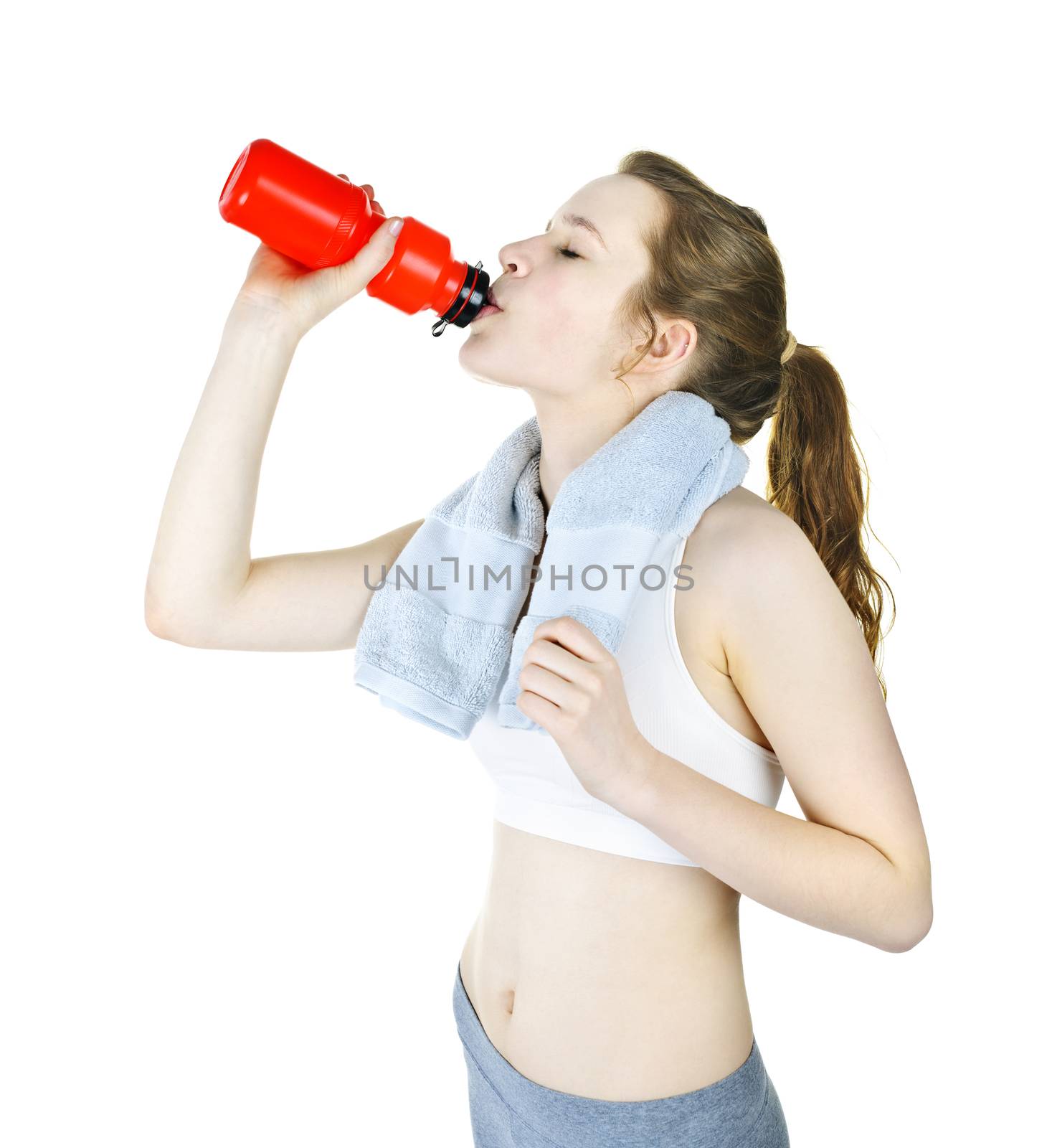 Happy fit young woman drinking from water bottle after workout