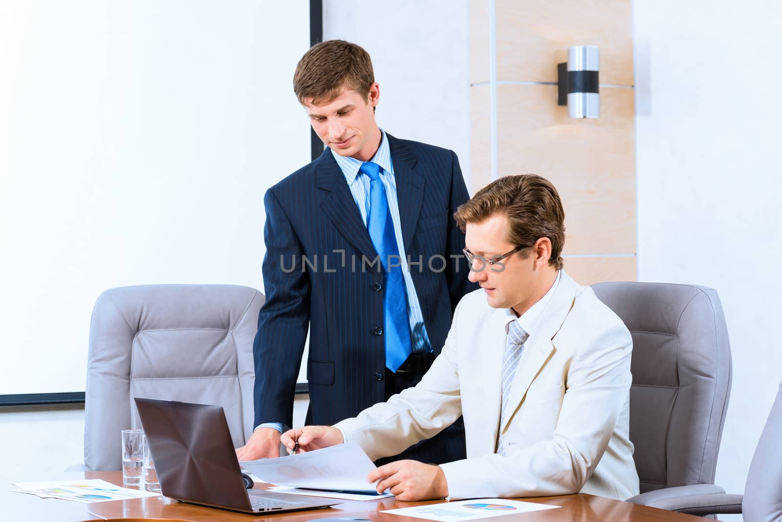 Business people talking, sitting at the table, watching the presentation on a laptop