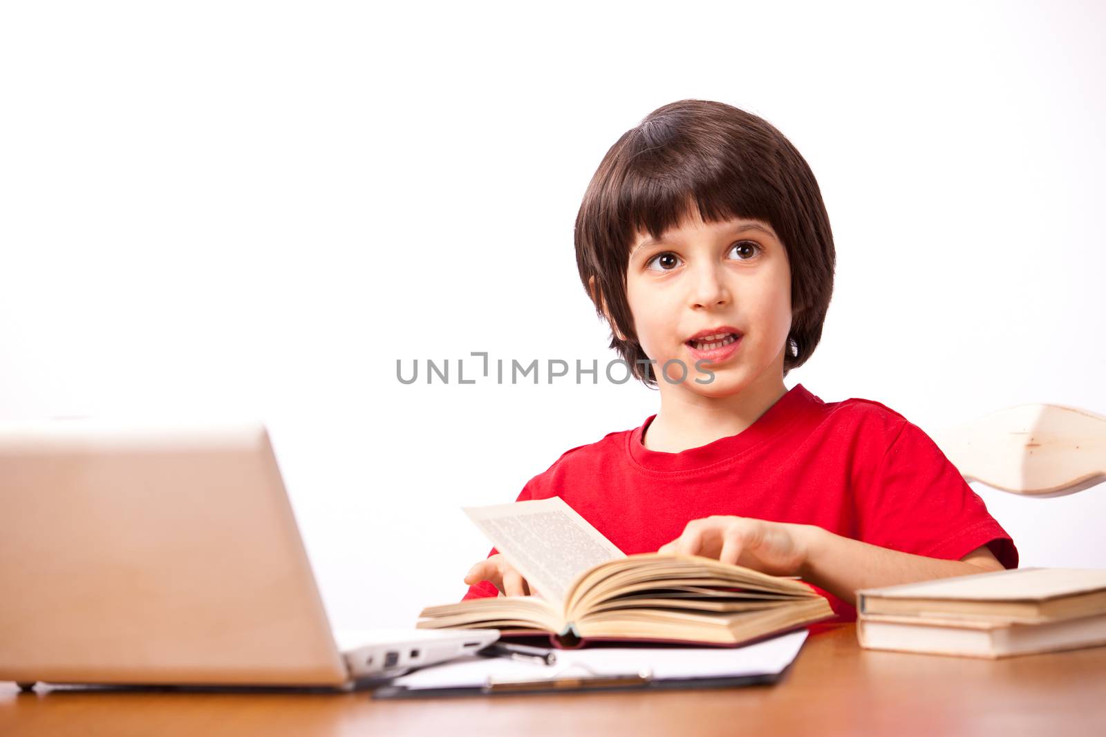 little boy in red t-shirt with computer and textbooks on white background