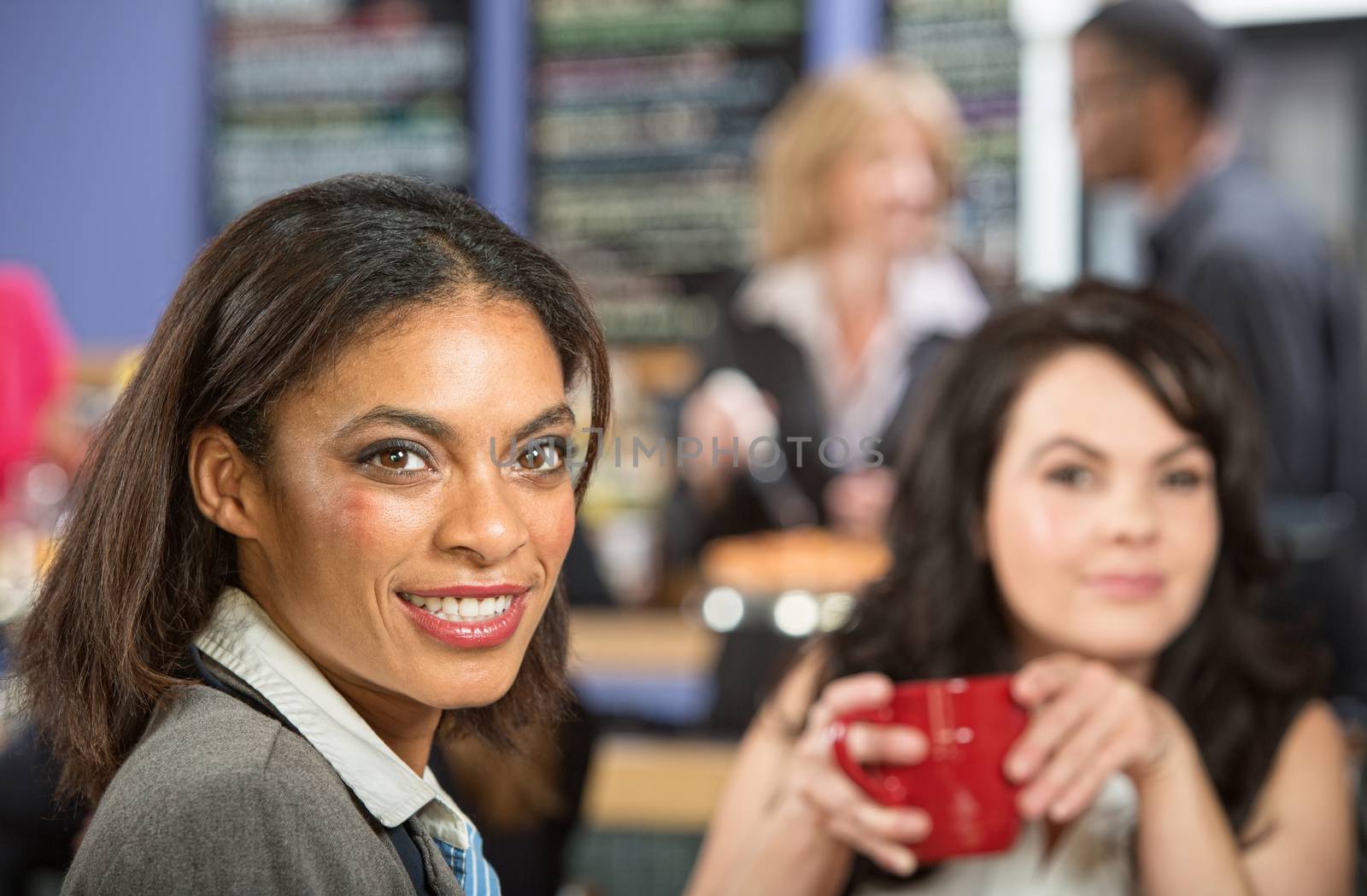 Two happy businesswomen with coffee mug in cafe