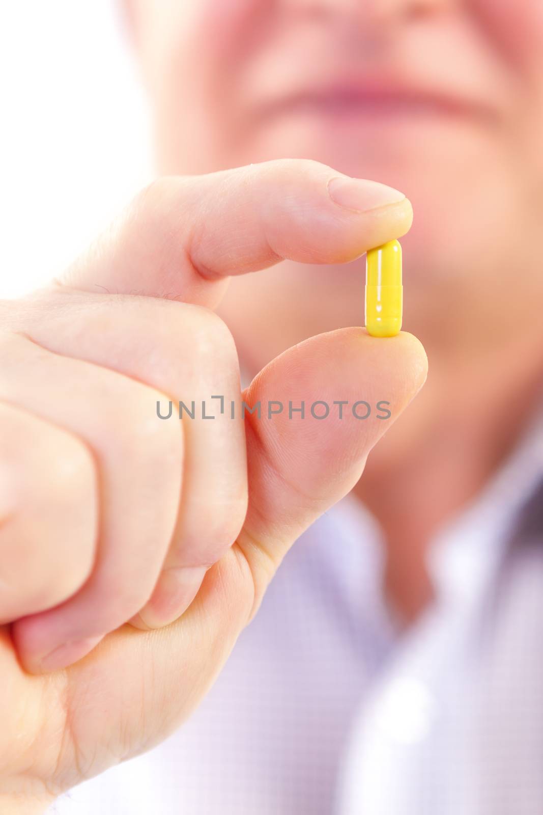 Senior adult man holds medicine capsule in his hand