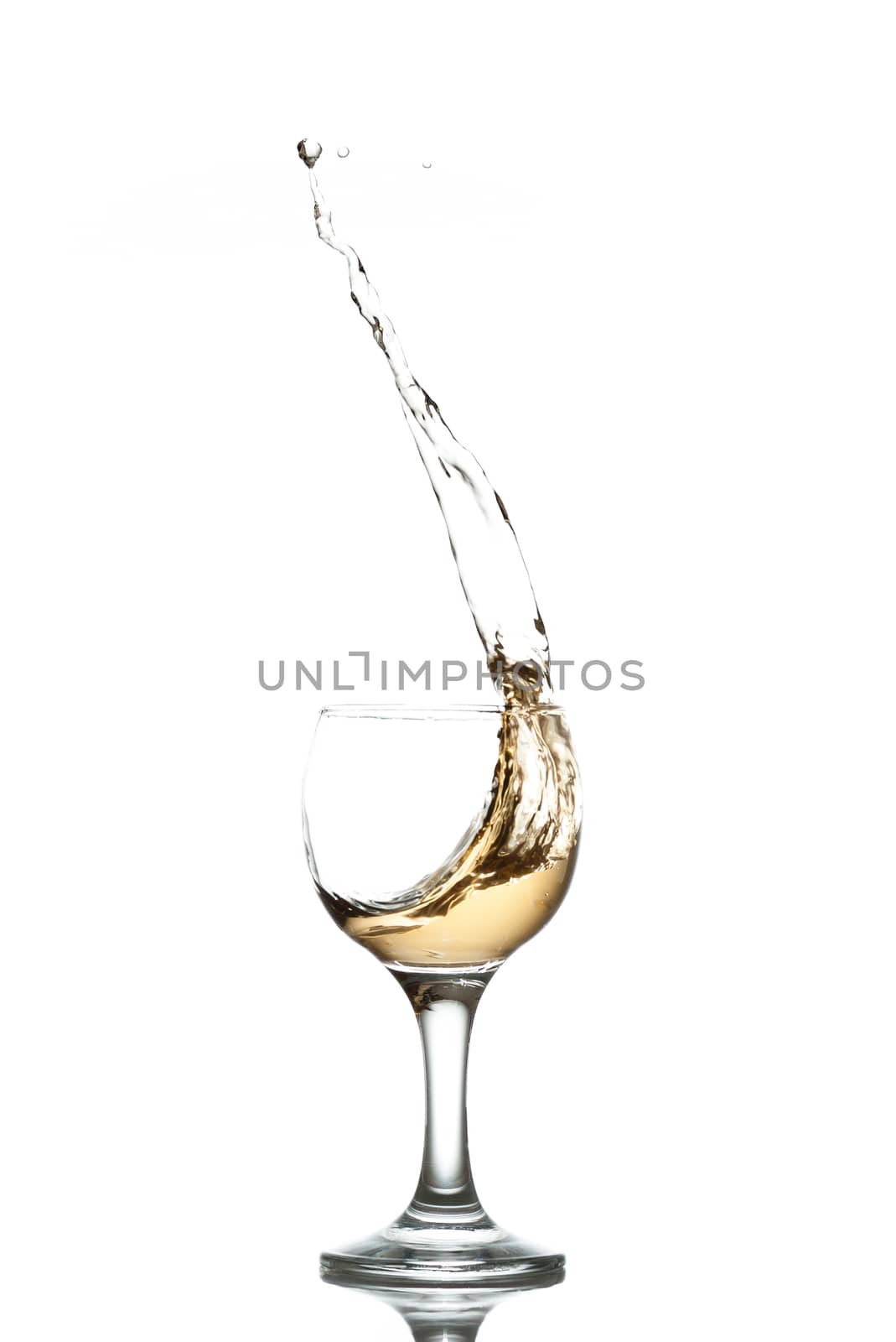 yellow drink splashes out of glass on white background