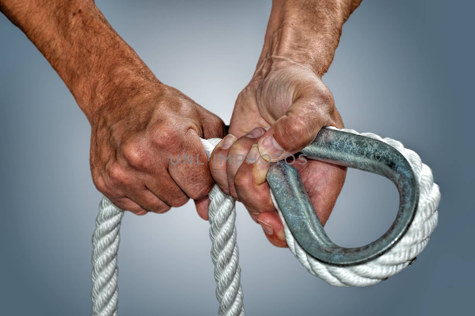 A pair of strong hands working witha big rope and a thimble