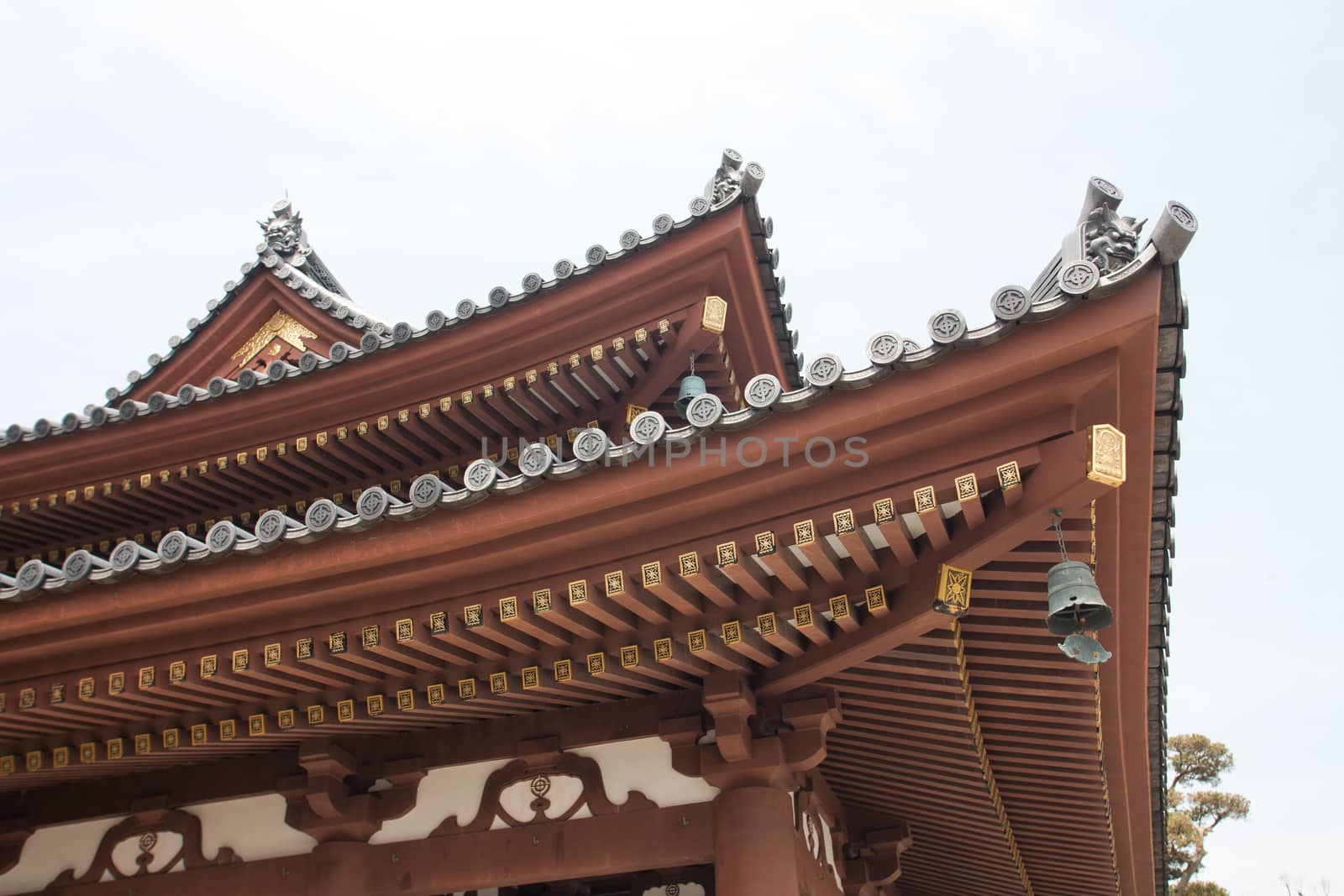 Detail on japanese temple roof against blue sky.