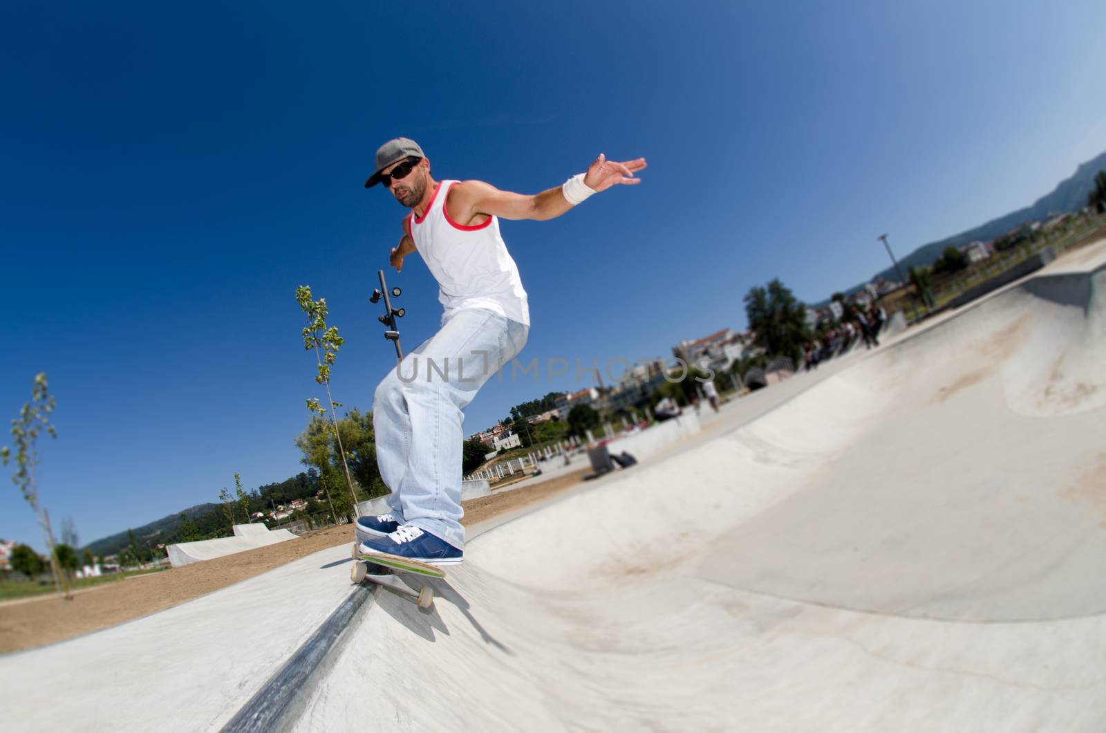 Skateboarder in a concrete pool at skatepark on a sunny day.