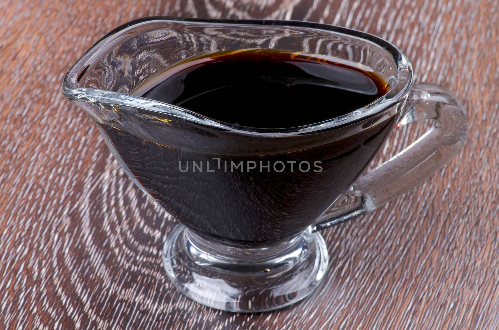 Soy Sauce in in Glass Gravy Boat isolated on Wooden background