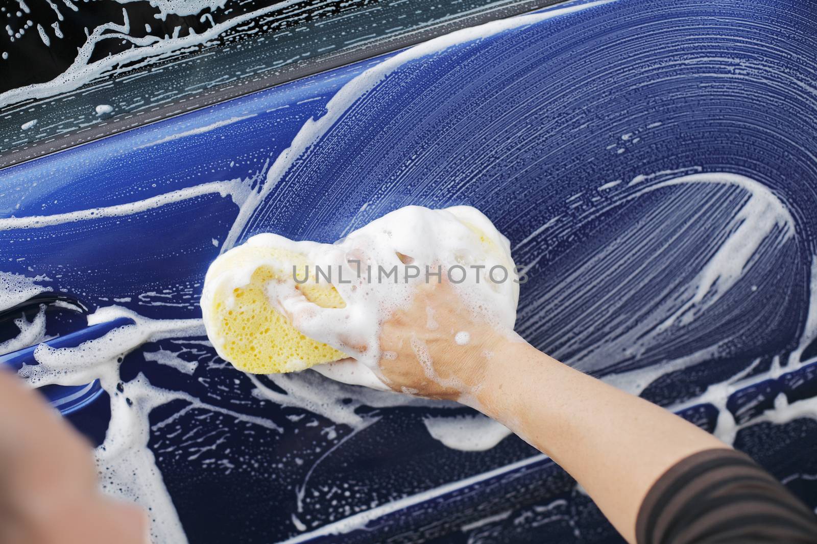 A man washing a car door with a sponge