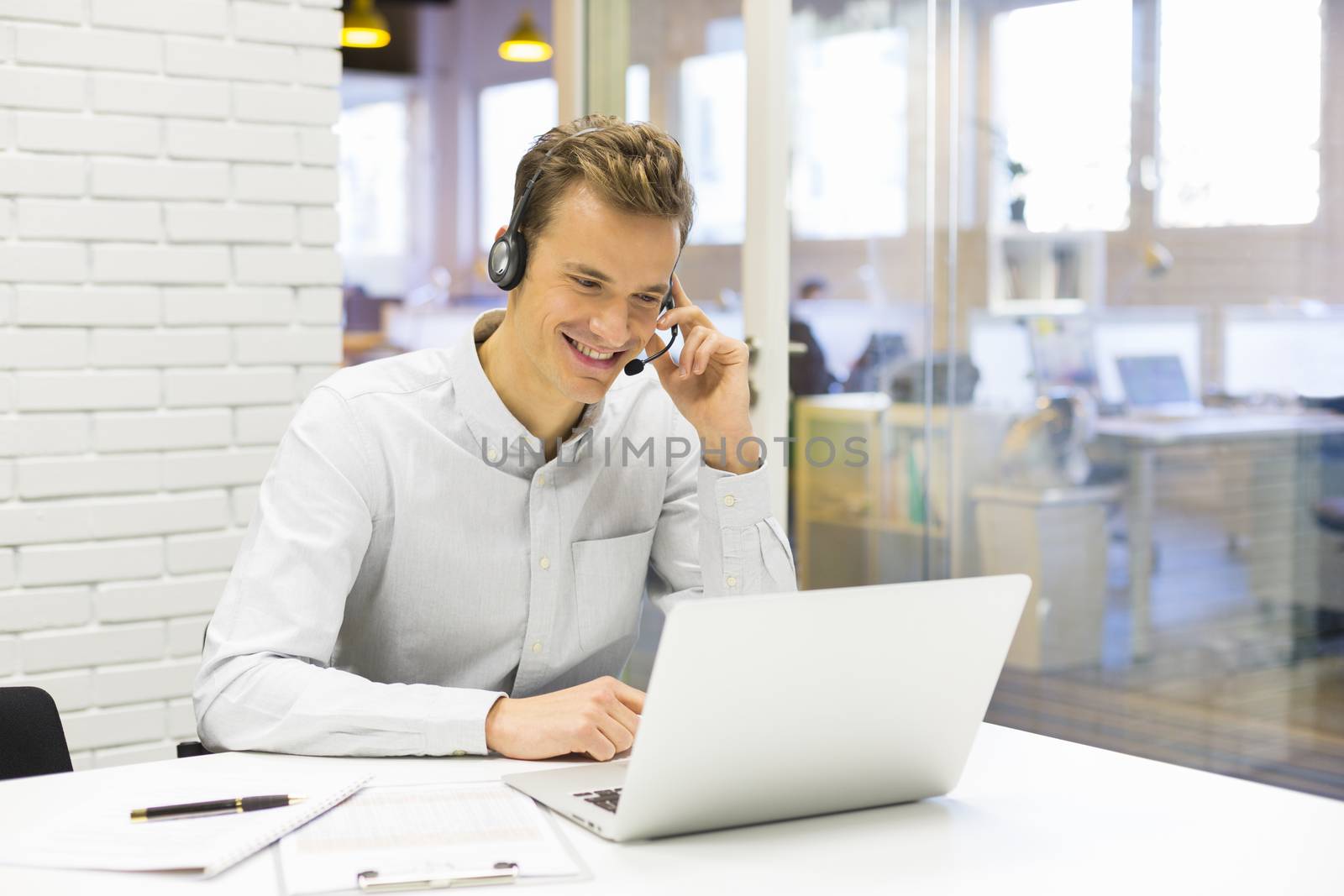 Businessman in the office on the phone with headset, Skype by LDProd