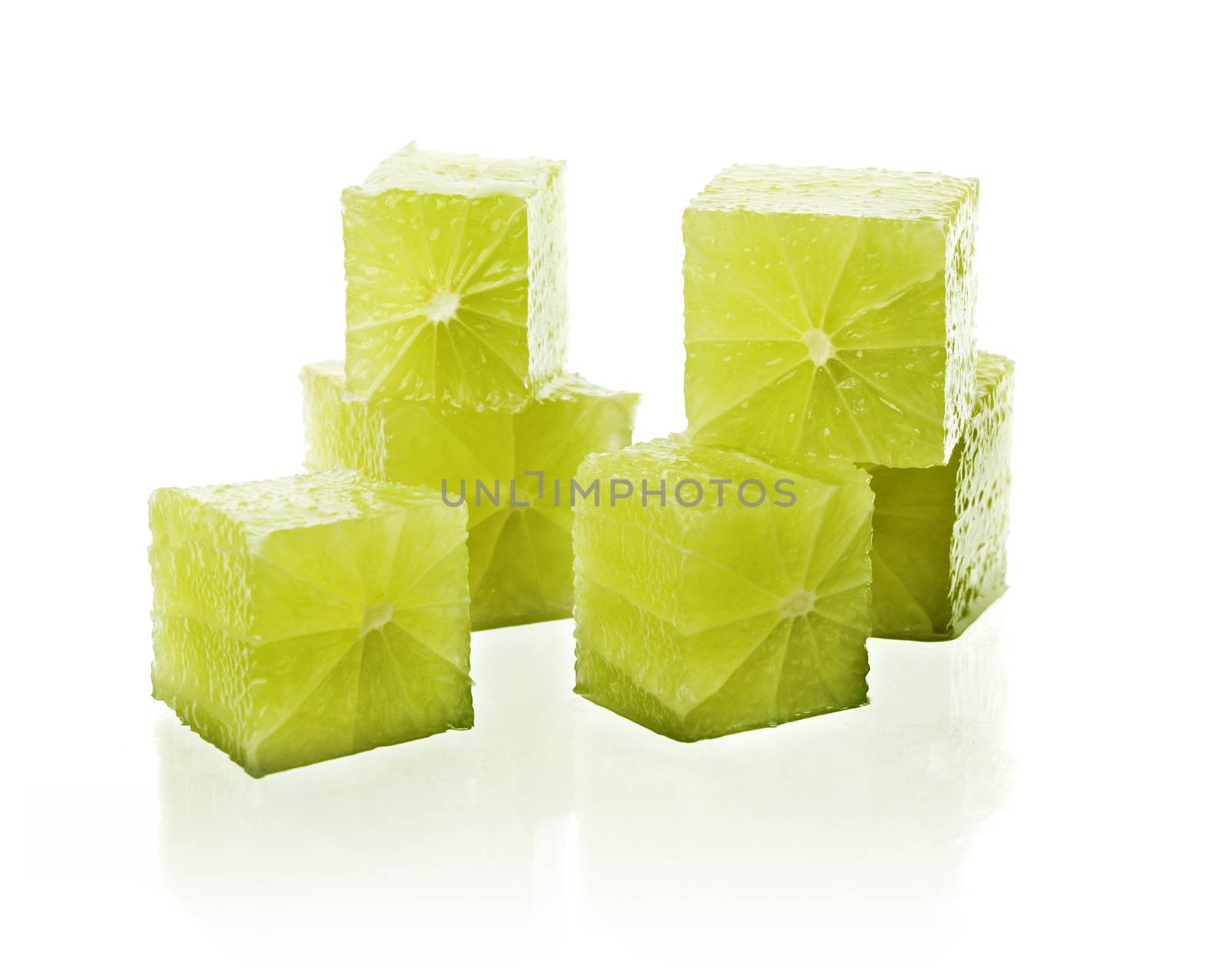 Real lime fruit cut into cubes on reflective white background.