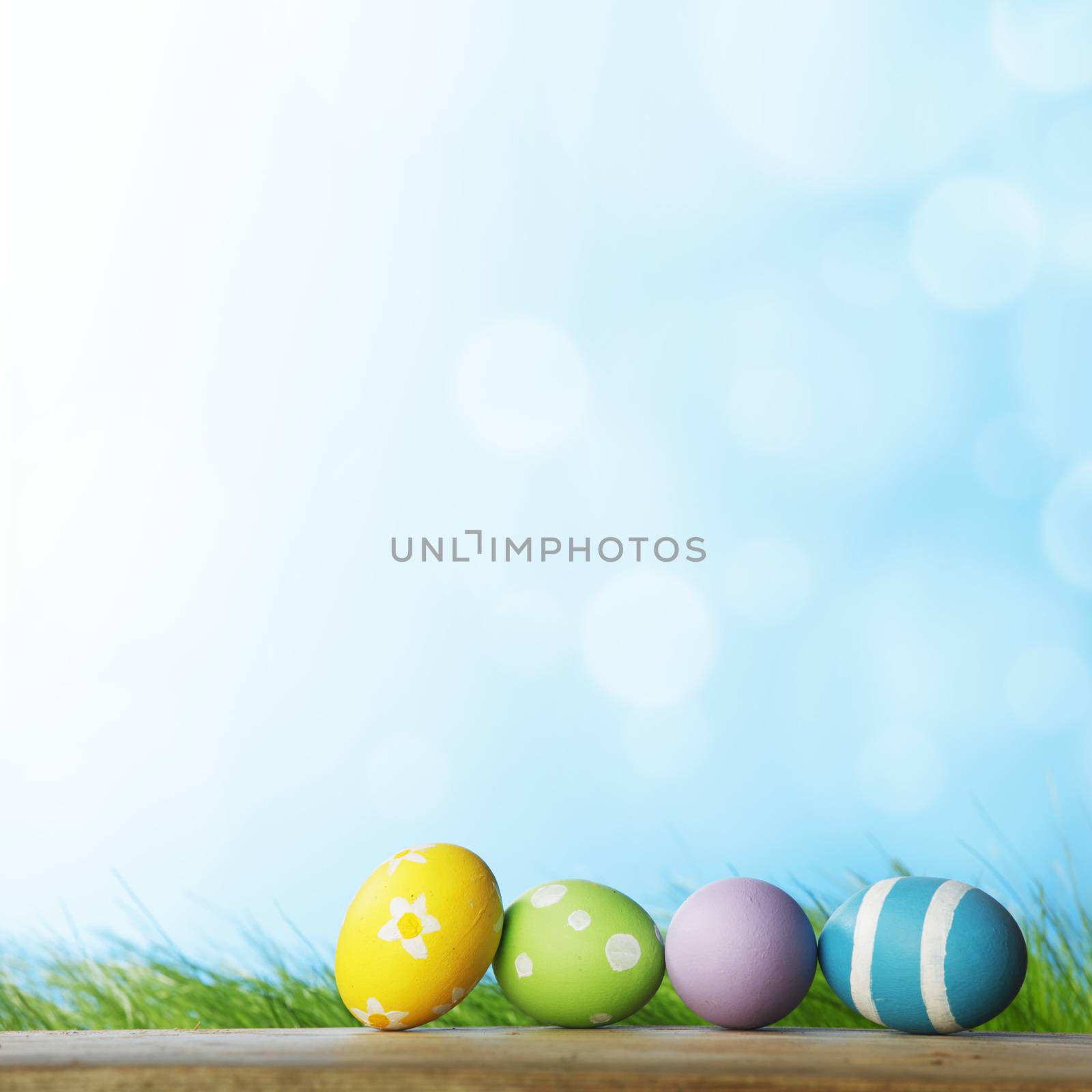 Row of Easter eggs on Fresh Green Grass and blue sky background