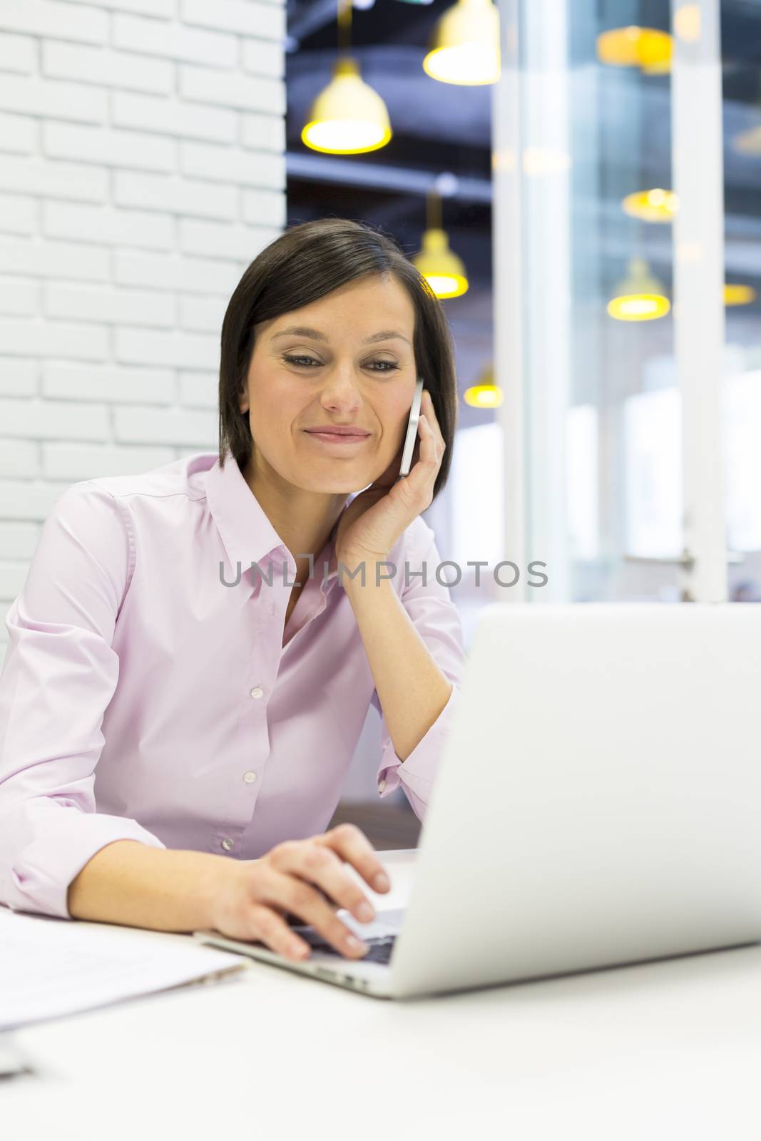 Pretty businesswoman on mobile phone in office by LDProd