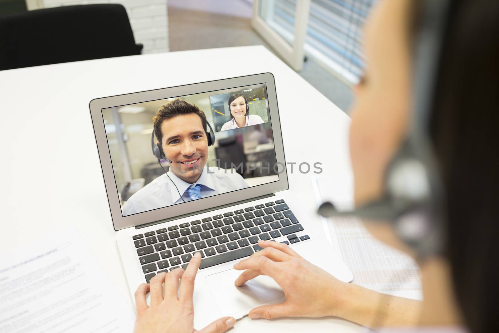 Businesswoman in the office on videoconference with headset, Sky by LDProd