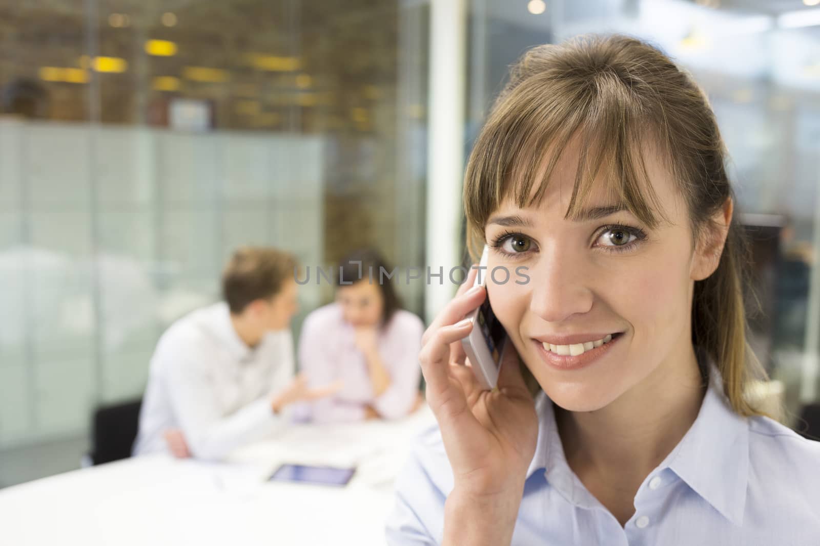 Portrait of smiling businesswoman on mobile phone in meeting by LDProd