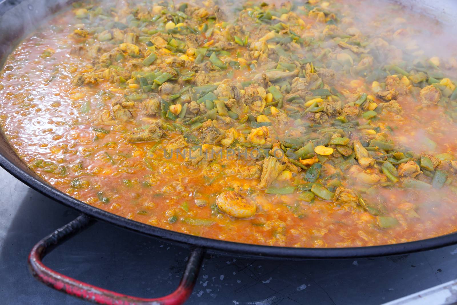 Cooking paella typical from Valencia Spain recipe with rice beans chicken and good hand