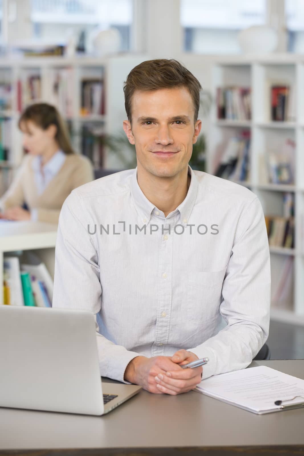 Portrait of smiling businessman working on laptop in office, loo by LDProd