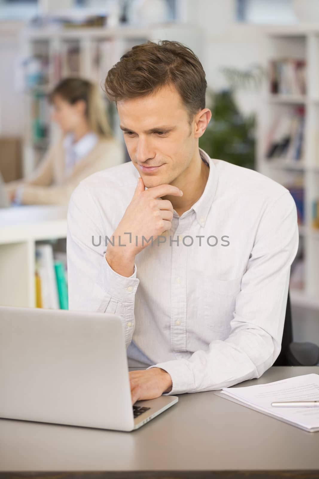Portrait of smiling businessman working on computer in office by LDProd