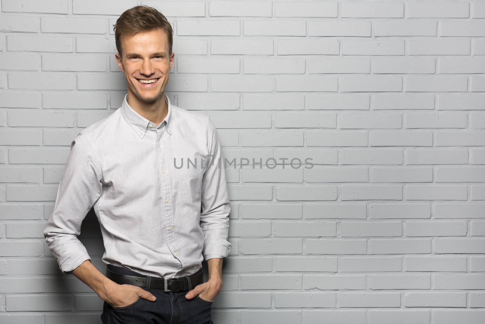 Portrait of Handsome smiling man, isolated over a gray brick wal by LDProd