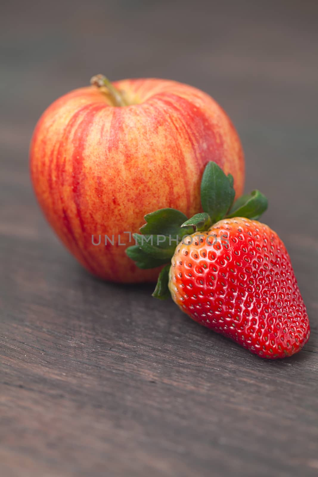  juicy apple and strawberry on a wooden surface
