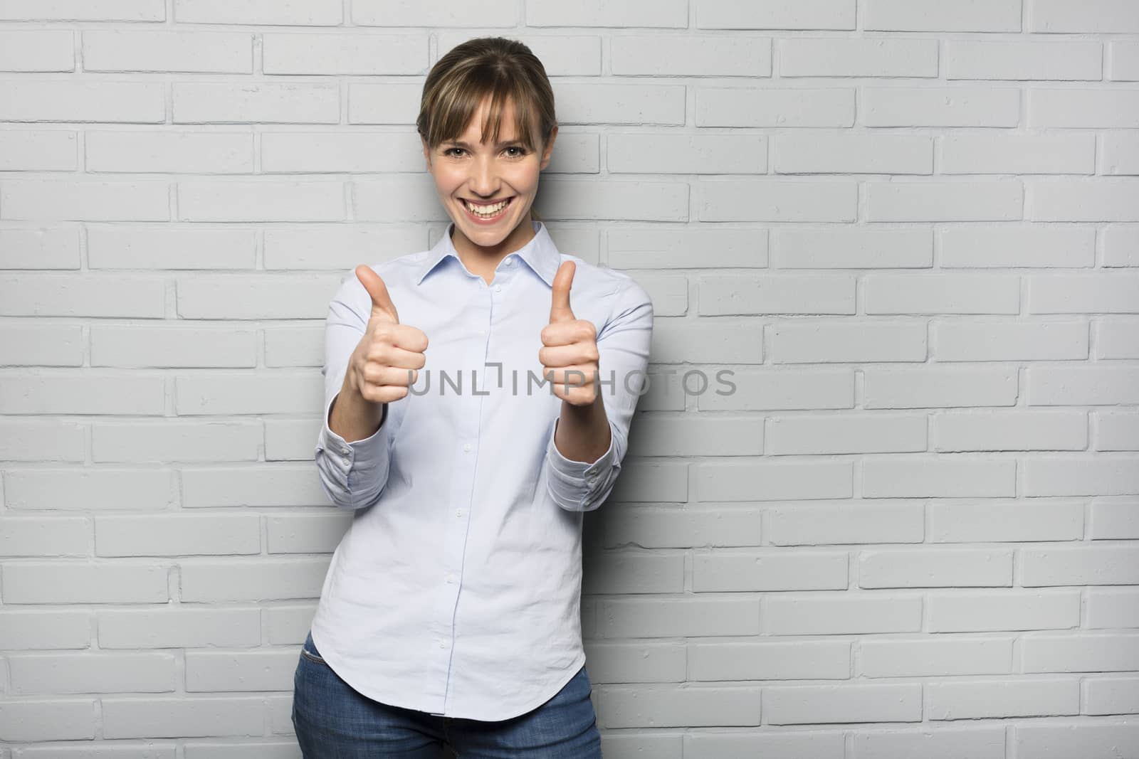 Happy Young Woman Showing Thumbs Up Sign isolated over a wall by LDProd