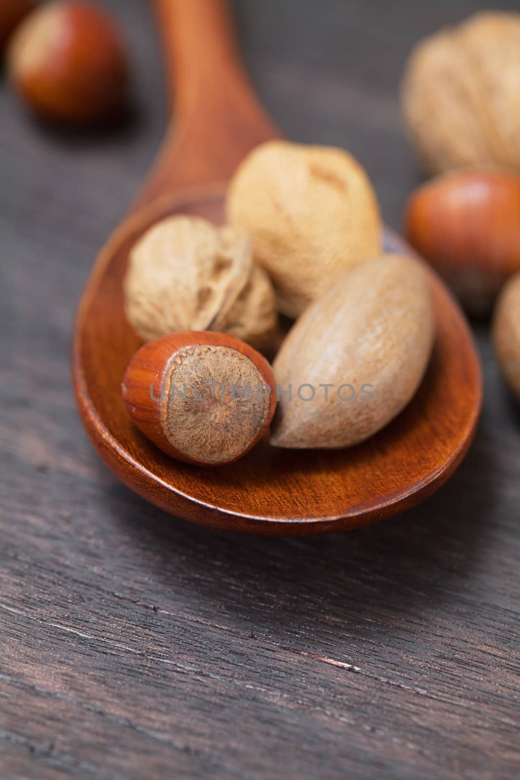 wooden spoon with nuts on a wooden surface by jannyjus