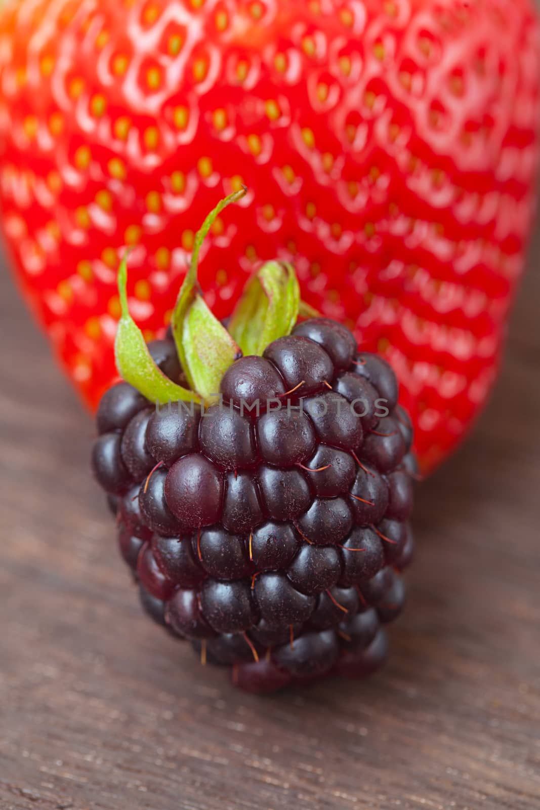 red juicy strawberry and blackberry on a wooden surface