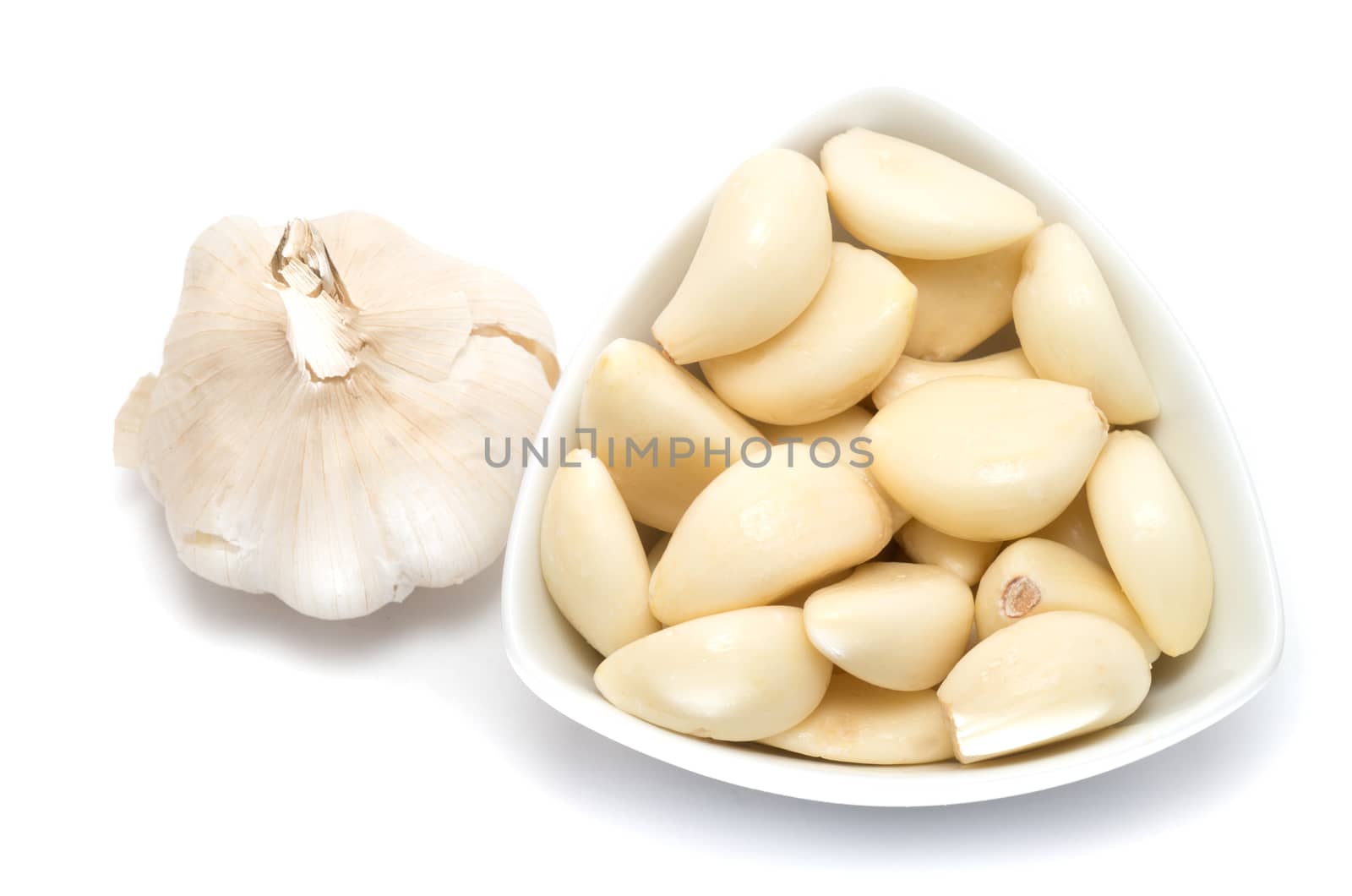 Garlic cloves and bulb in a ceramic bowl on white background