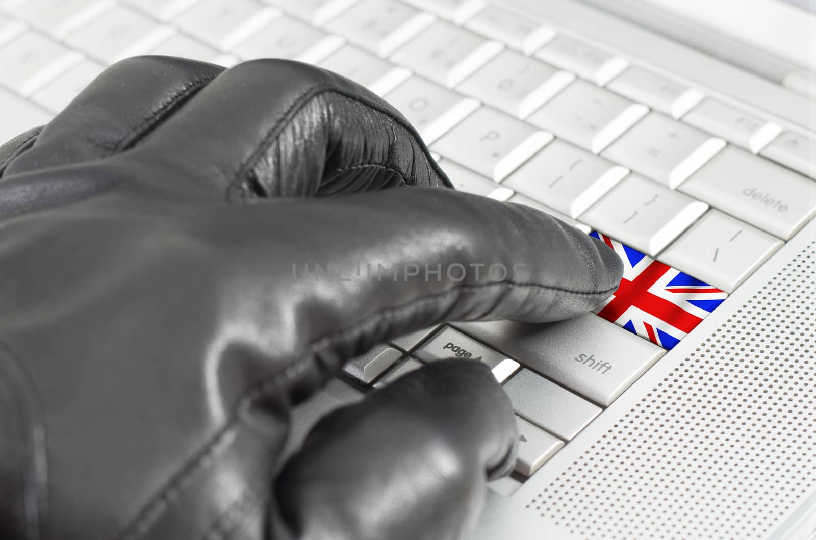 Hacking UK concept with hand wearing black leather glove pressing enter key with flag overlaid