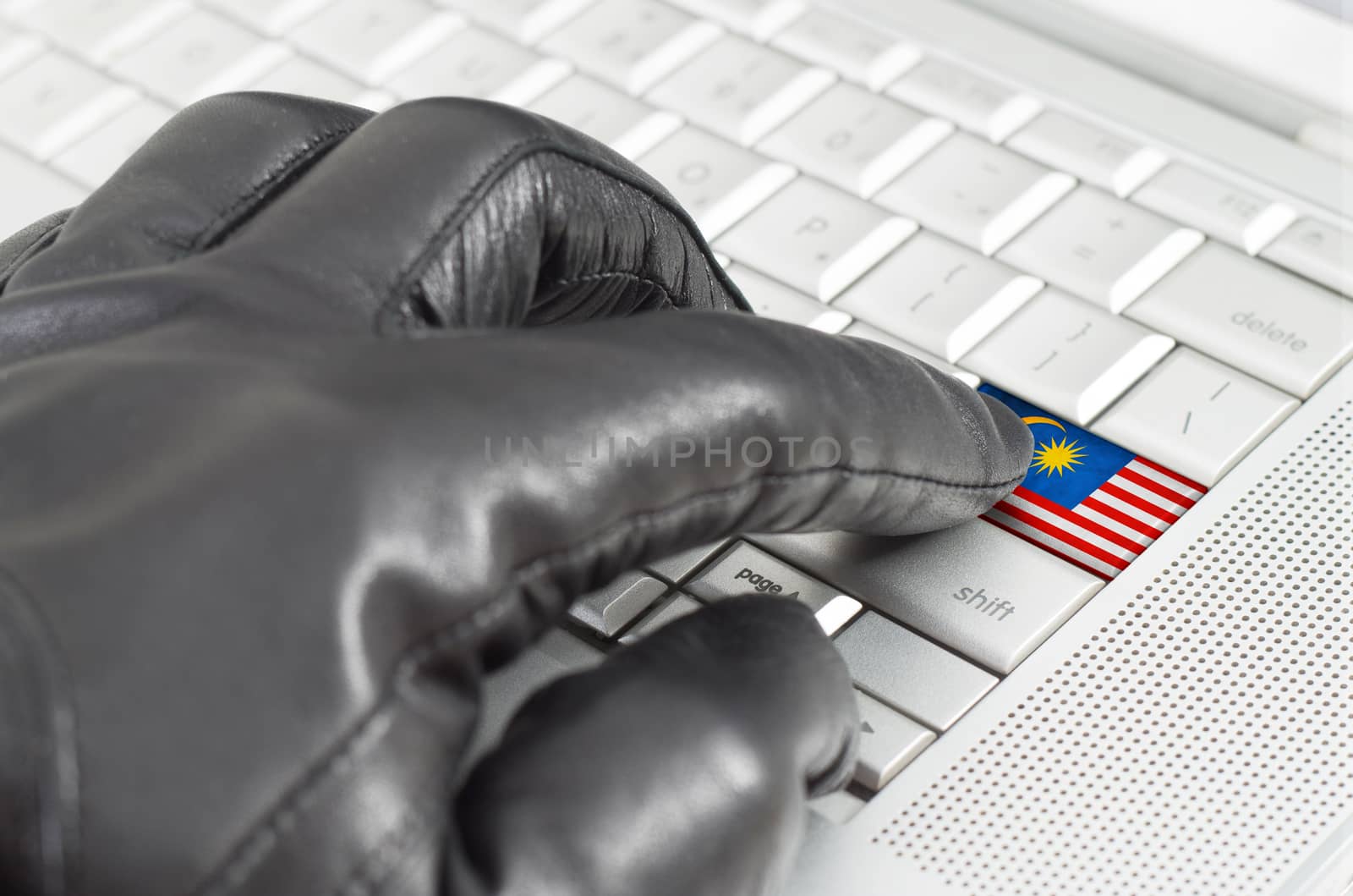 Hacking Malaysia concept with hand wearing black leather glove pressing enter key with flag overlaid