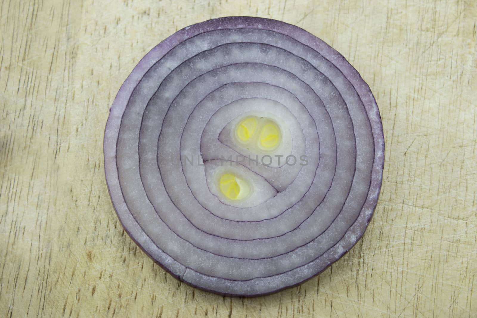 Red sliced onion on wooden kitchen board.