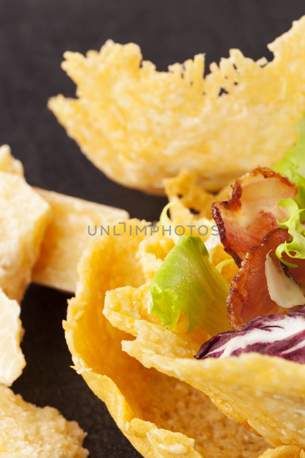 Parmigiano cheese basket filled with colorful vegetable and bacon. Luxurious cheese eating.