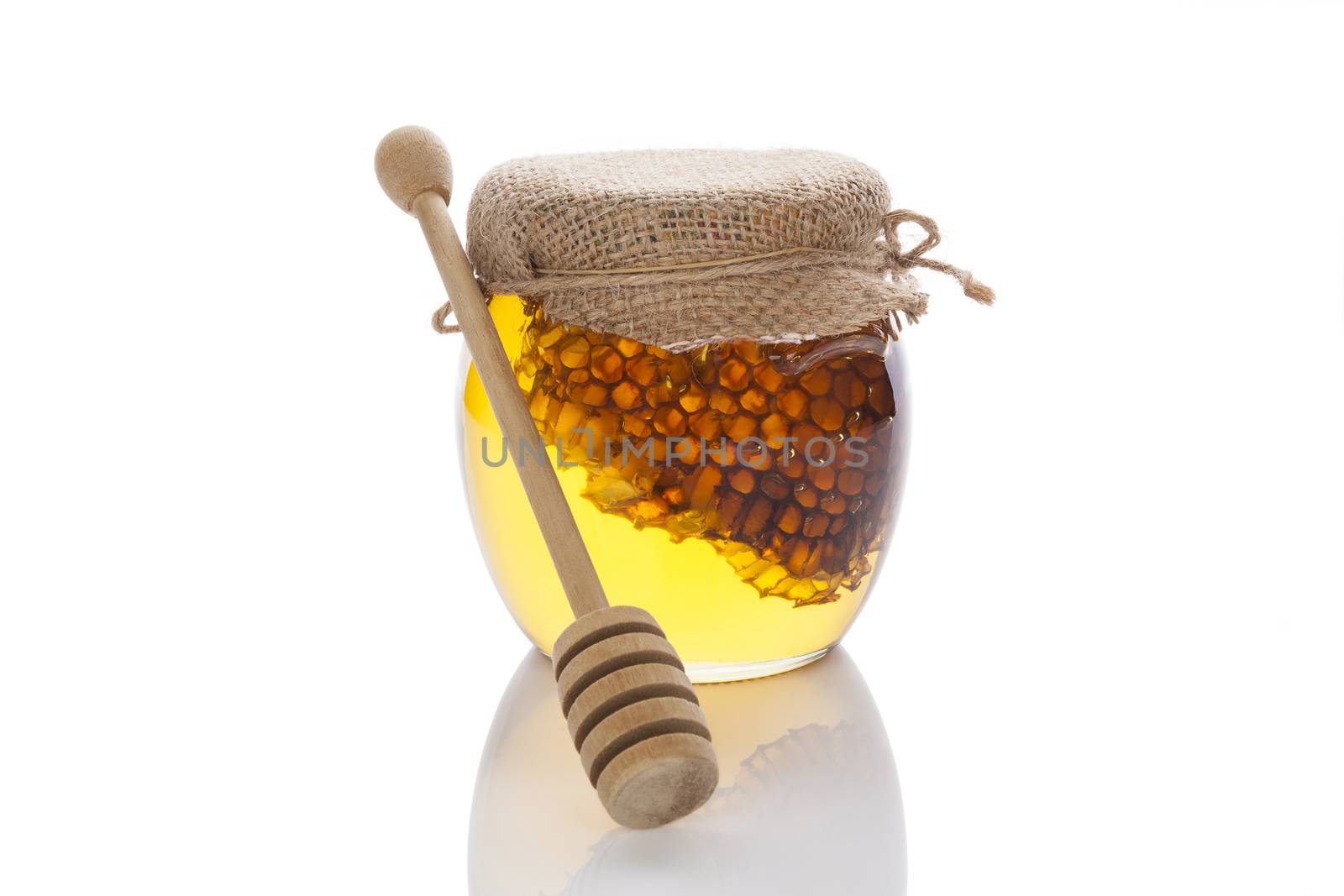 Honey in glass jar with wooden dipper and honey comb isolated on white background. Organic bee honey.