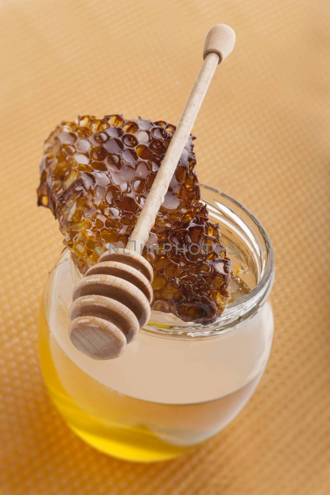 Golden organic honey in glass jar on golden honey comb. Natural organic honey concept. Healthy eating. 