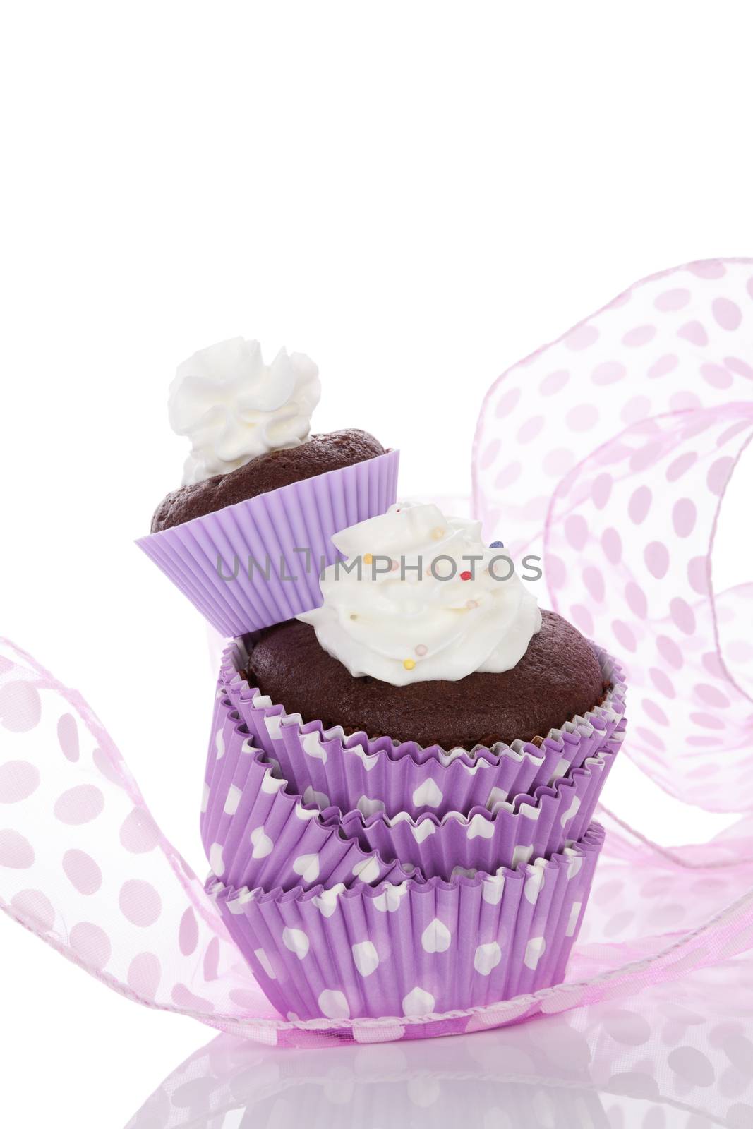 Delicious chocolate cupcake with whipped cream in purple dotted paper form isolated on white. Cupcakes baking.