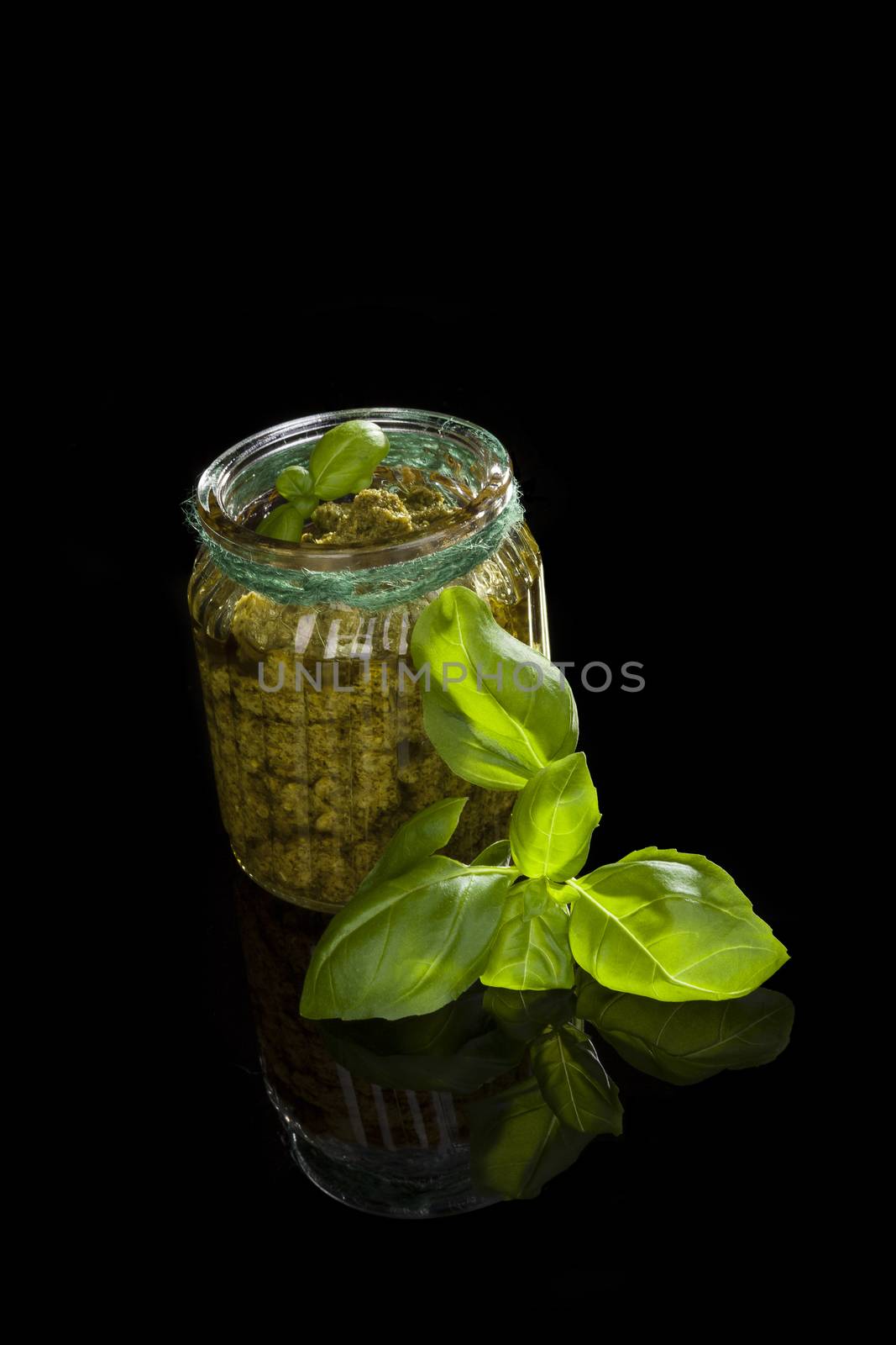 Green basil pesto isolated on black background. Culinary traditional mediterranean vegetarian eating.