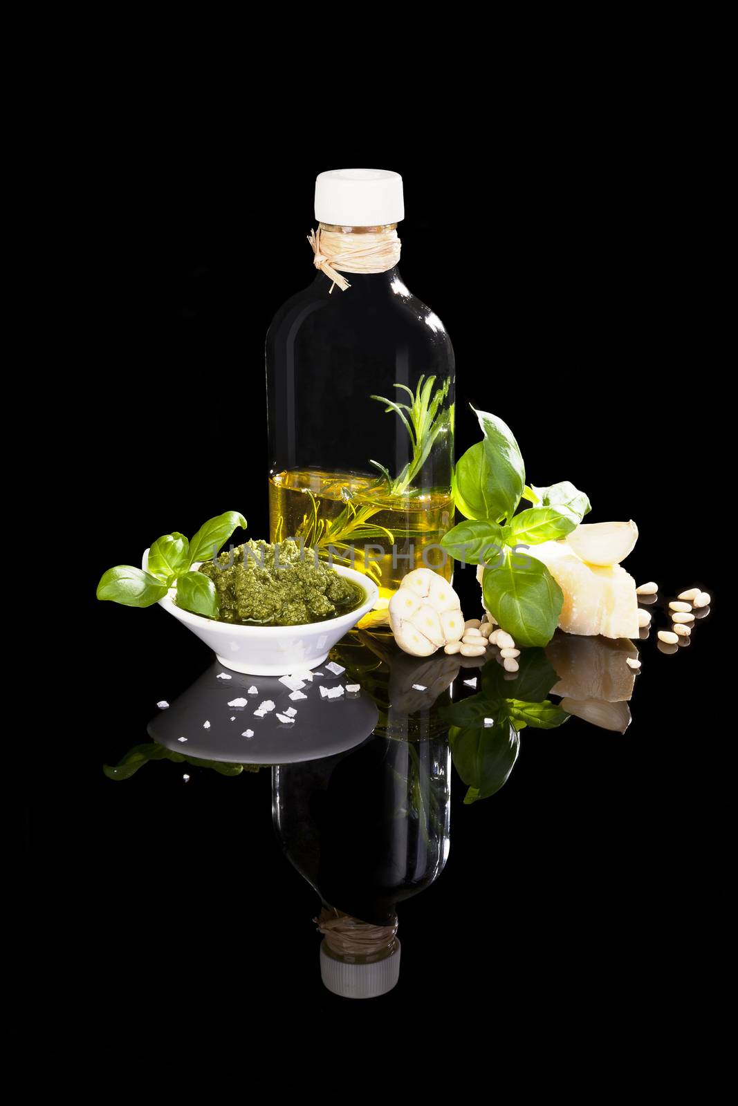 Culinary italian eating. Olive oil, fresh green pesto, garlic, salt and fresh green herbs isolated on black background. Organic mediterranean eating.