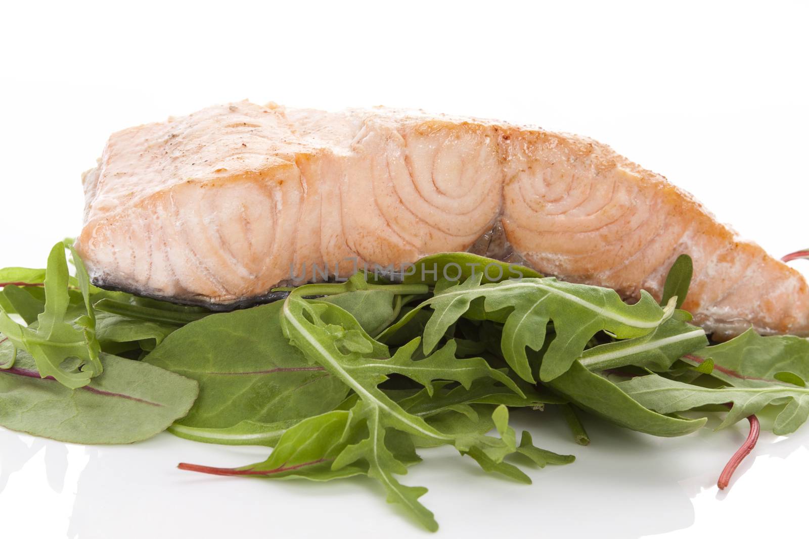 Salmon steak on green salad on white background. Healthy fish eating.