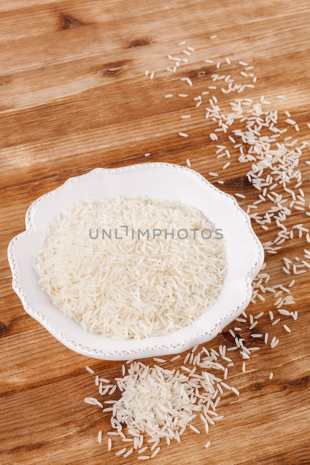 Rice in white vintage bowl on wooden background. Traditional rice eating, rustic style.