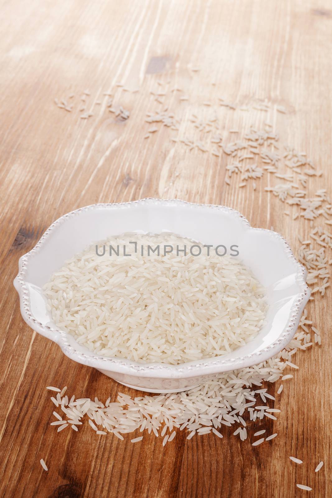 Traditional asian rice eating. Raw rice in white bowl in brown wooden background. Culinary healthy rice eating.