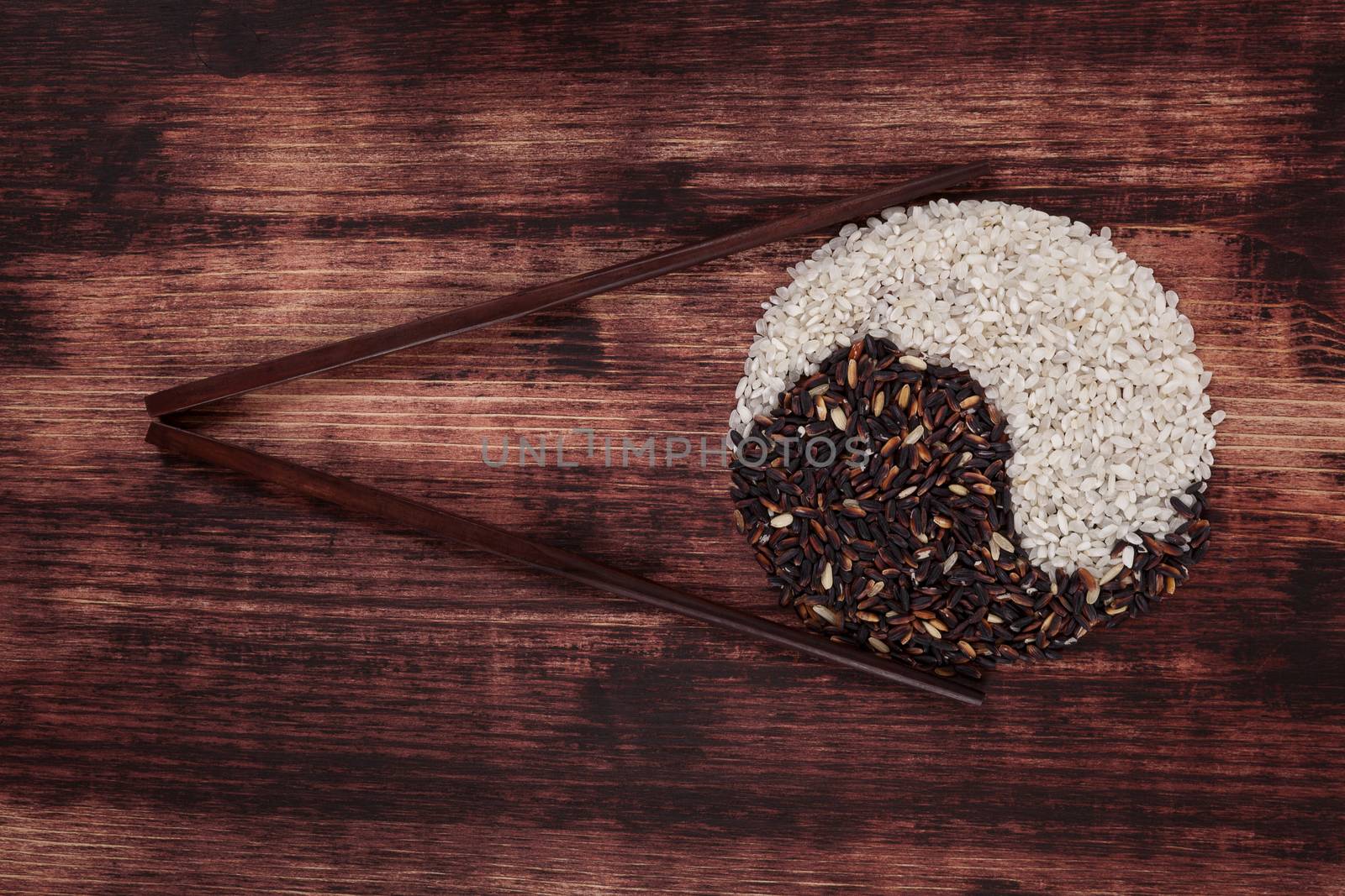 White and black rice with chopsticks on dark wooden background. Asian zen culture and eating. 