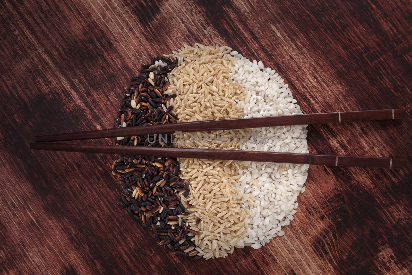 Rice variation of organic rice with chopsticks on dark wooden background. Healthy rice cooking concept.
