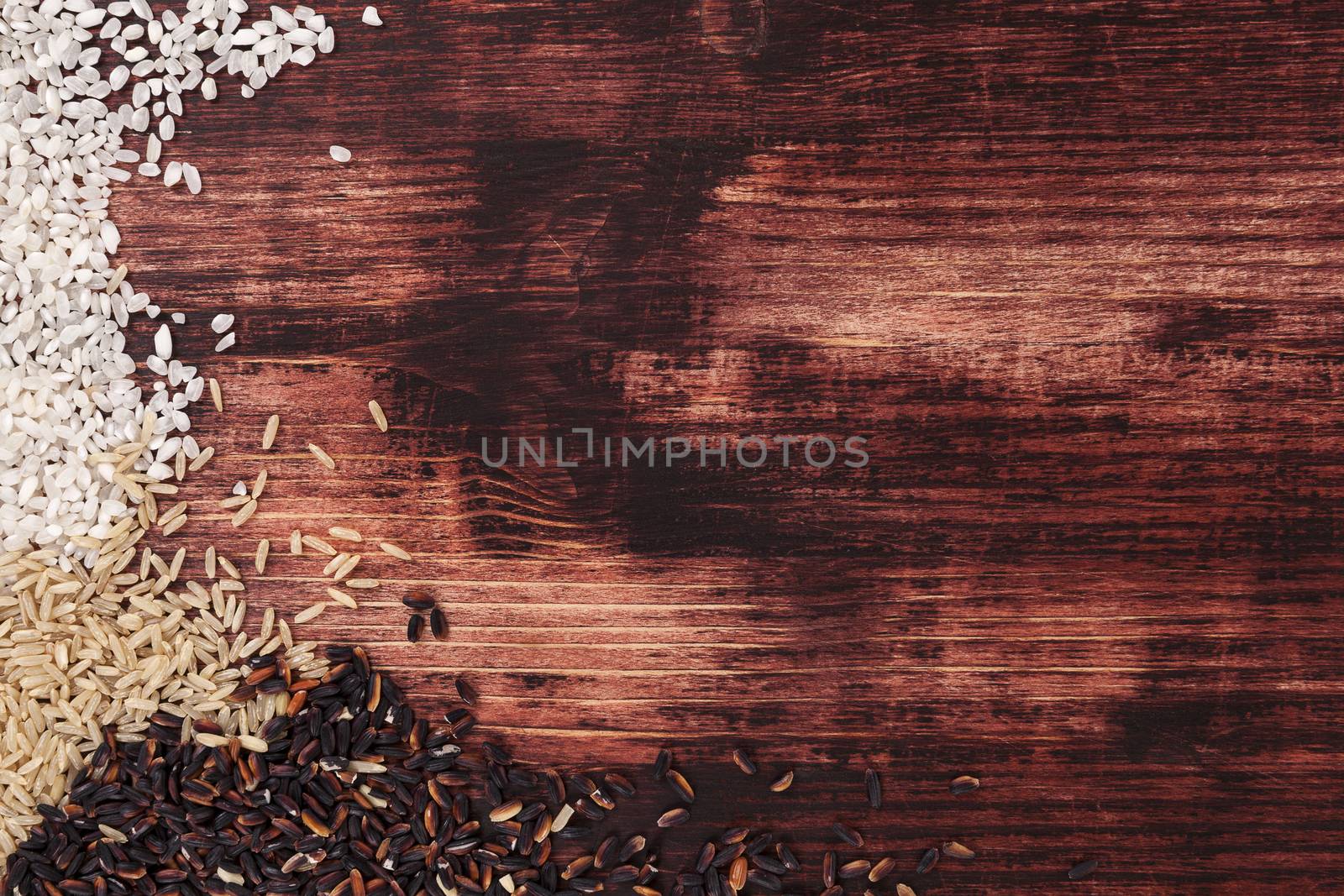 White, natural and wilde rice on dark wooden background. Healthy rice background with copy space.