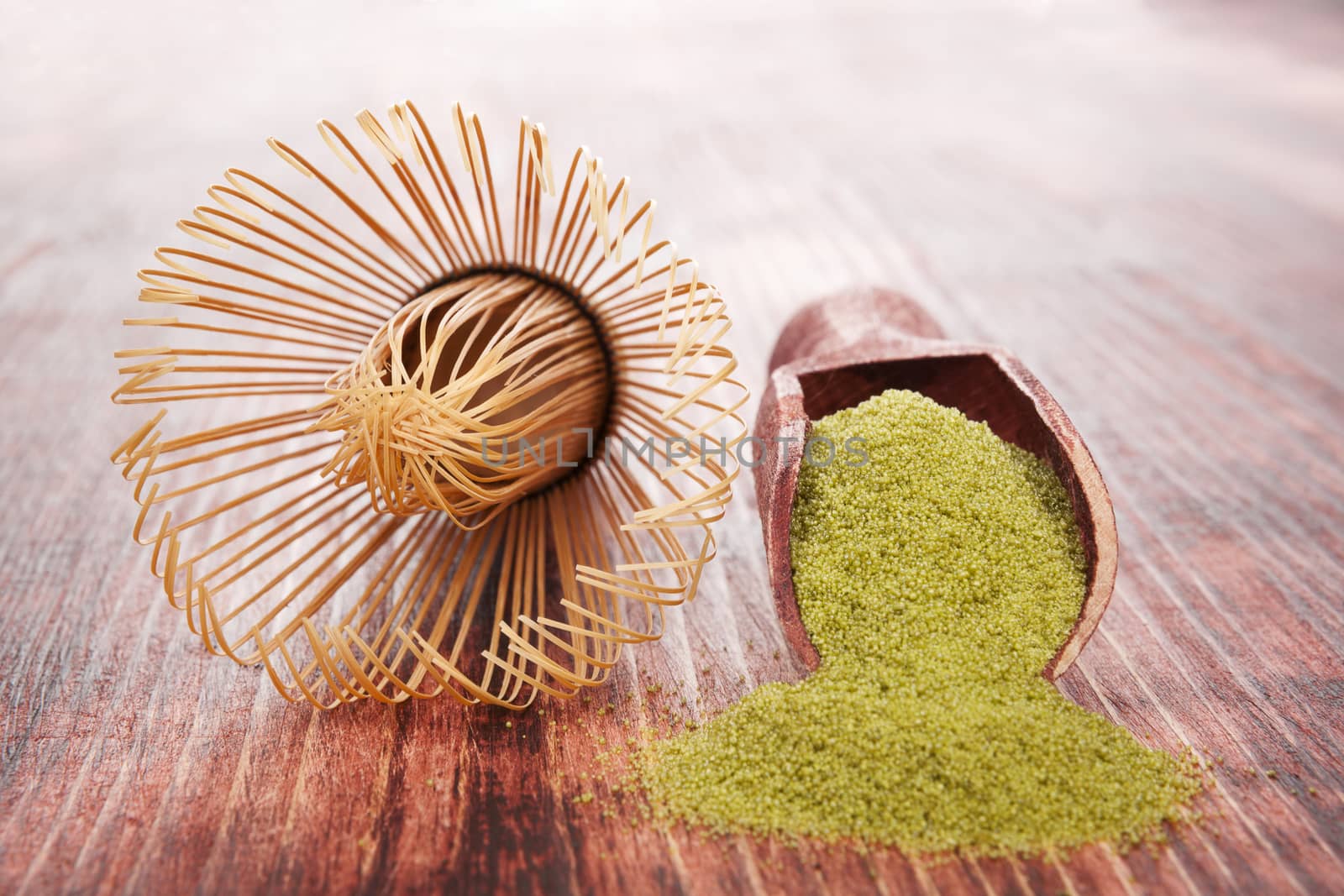 Matcha. Green powdered tea on wooden background with wooden scoop. Traditional healthy asian beverage.
