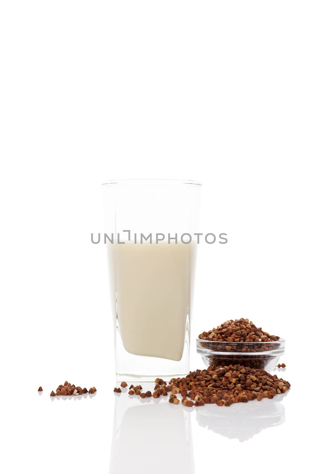 Buckwheat milk in glass with dry buckwheat seeds in glass bowl isolated on white background. Vegan and vegetarian milk concept.