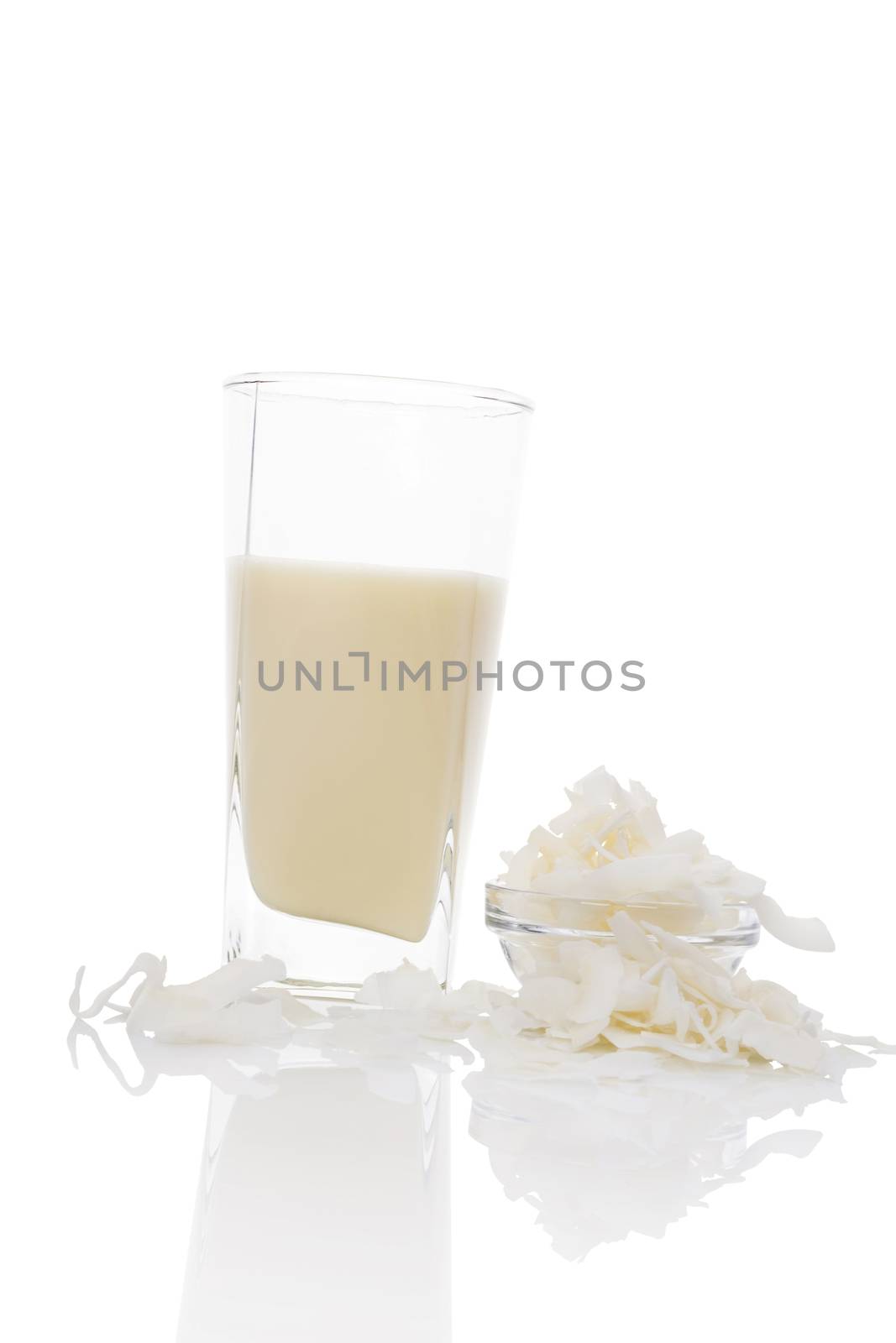 Coconut milk in glass with coconut flakes in glass bowl isolated on white background. Vegan and vegetarian milk concept.